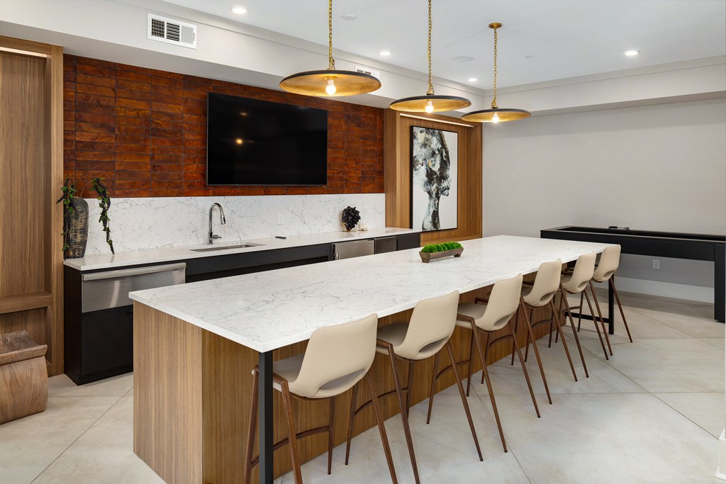 the kitchen has a large marble counter top and a long island with chairs