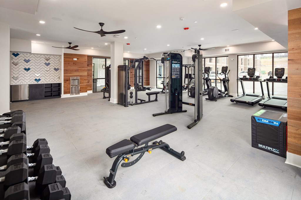 a gym with weights and cardio equipment in a building with windows