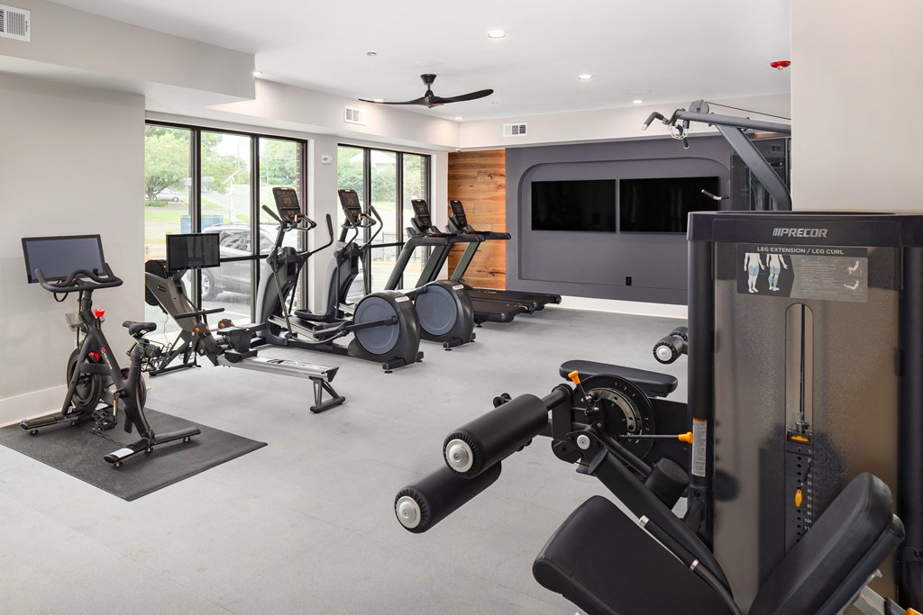 a gym with various exercise equipment and a tv in the corner
