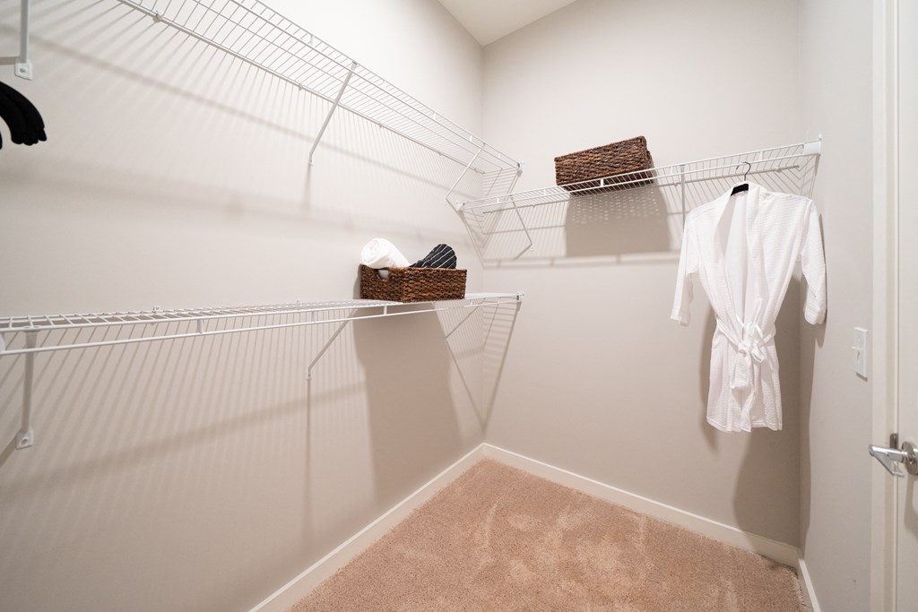 a spacious walk in closet with a white robe and hanging racks