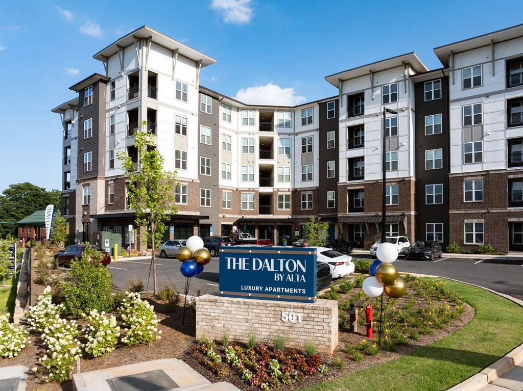 The Dalton by Alta Luxury Apartments is a large, modern building with a well-maintained garden in front.