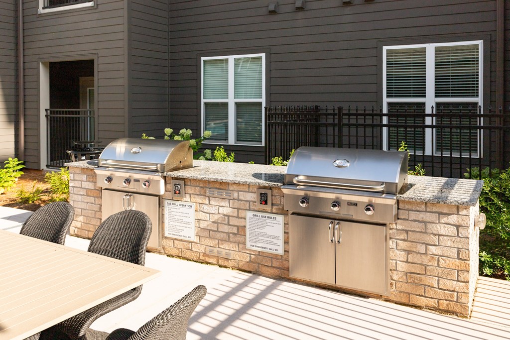 A brick wall with a grill on top and a table and chairs in front.