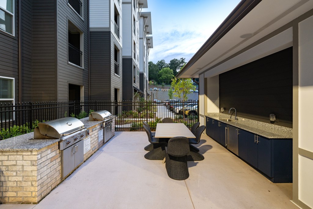 A patio with a table and chairs is surrounded by a black fence and a brick wall.