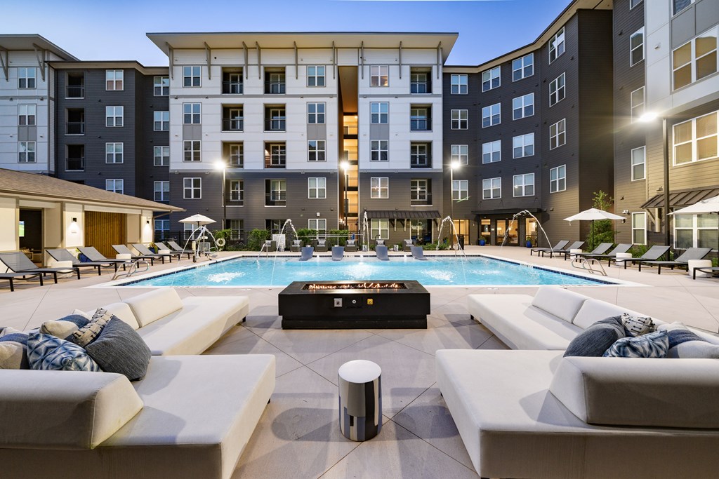 A large outdoor pool surrounded by lounge chairs and umbrellas.