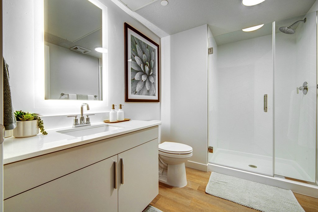 A white bathroom with a toilet, sink, and shower.