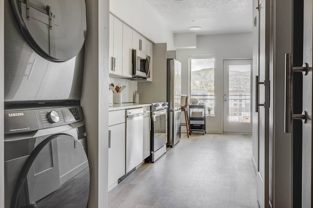 a kitchen with a washer and dryer and a door to a living room