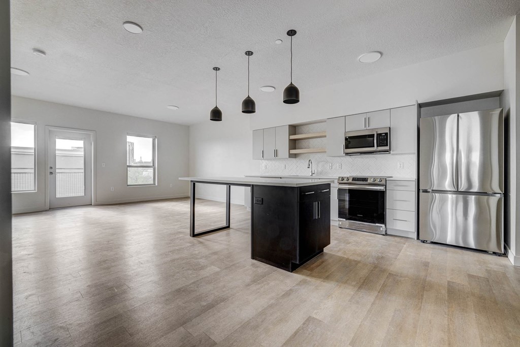 an empty kitchen and living room with stainless steel appliances and a island