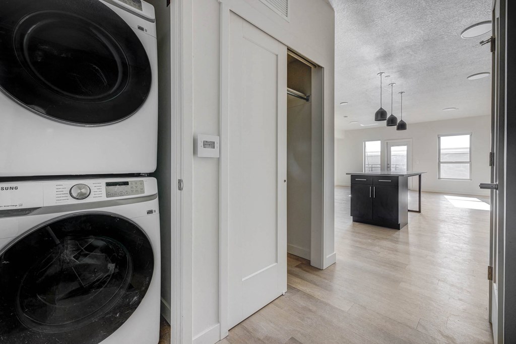 a  stacked white washer and dryer in an apartment home hallway