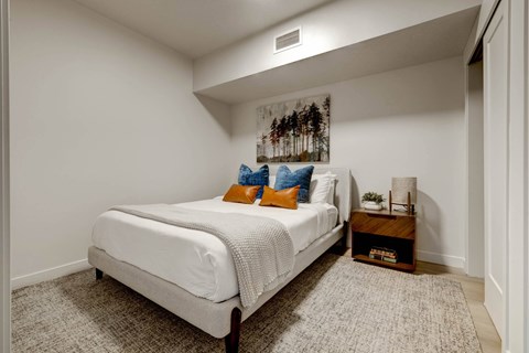 bedroom with white walls and a white bed with orange and blue pillows