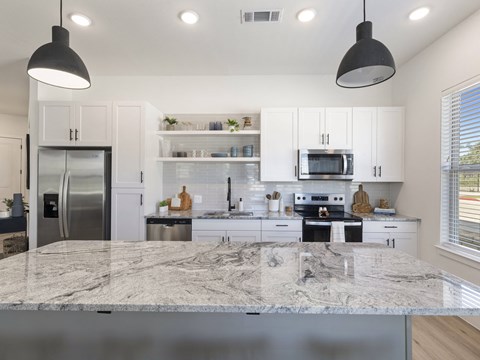 a kitchen with white cabinets and a marble counter top