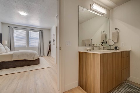 A bathroom with a vanity and a bedroom with a bed.