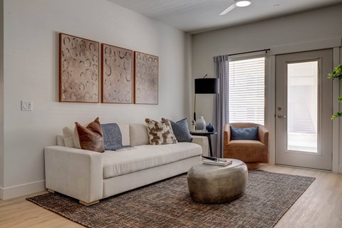 A living room with a white couch and a brown ottoman.