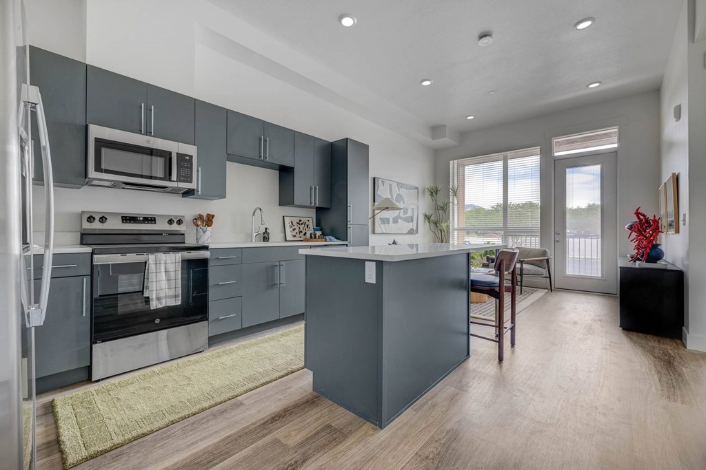 A modern kitchen with a refrigerator, oven, and microwave.