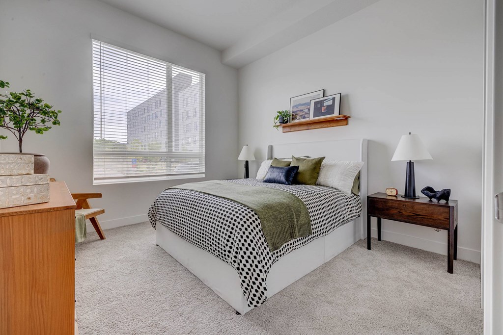 A bedroom with a bed, nightstand, and window.