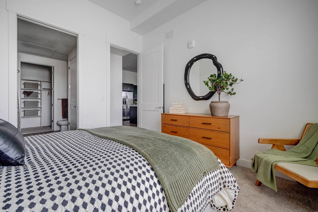 A bedroom with a bed, dresser, and chair.