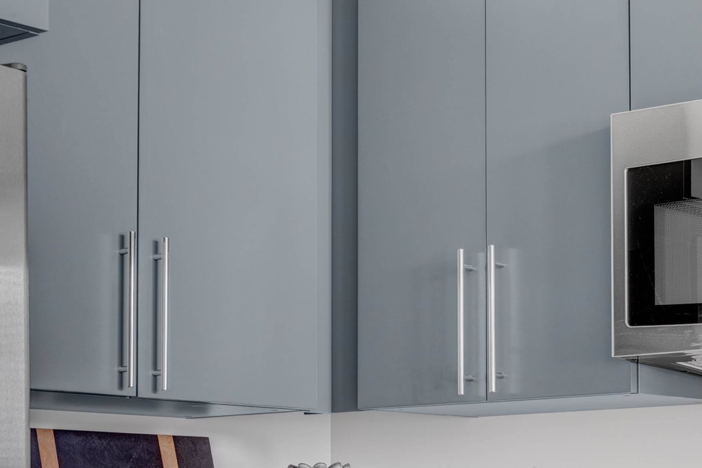 A kitchen with grey cabinets and a microwave.