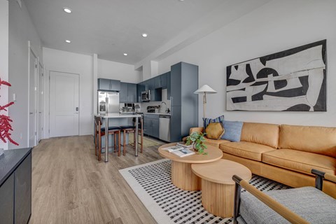 A modern living room with a tan sofa and a black and white abstract painting on the wall.