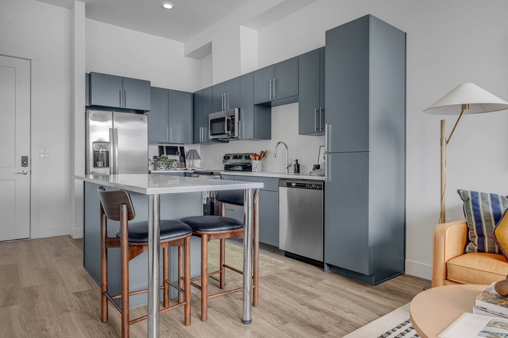 A modern kitchen with a bar stool and a dining table.