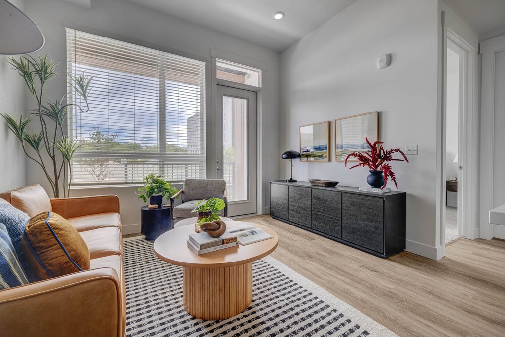 A living room with a brown sofa, a round table, and a black and white rug.