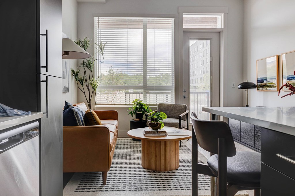 A modern living room with a brown sofa, a wooden coffee table, and a black chair.