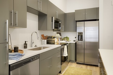 A modern kitchen with stainless steel appliances and grey cabinets.