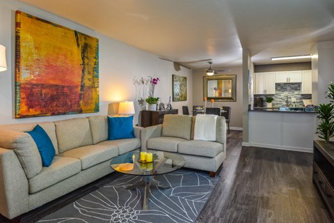 A living room with a grey couch, a coffee table, and a painting on the wall.