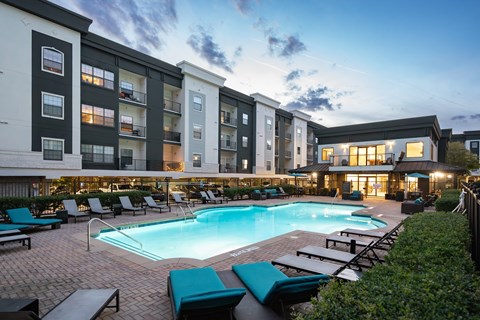 A large swimming pool surrounded by lounge chairs and umbrellas.