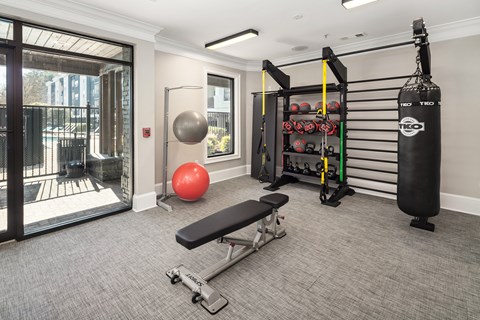 A gym room with a punching bag, weights, and exercise equipment.