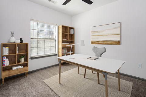 A room with a white desk, a bookshelf, and a painting on the wall.