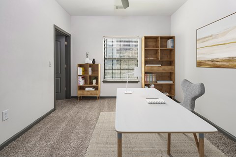 A room with a white table, a chair, and a bookshelf.