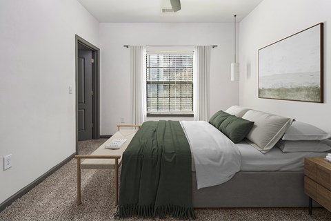 A bedroom with a bed, nightstand, and window.