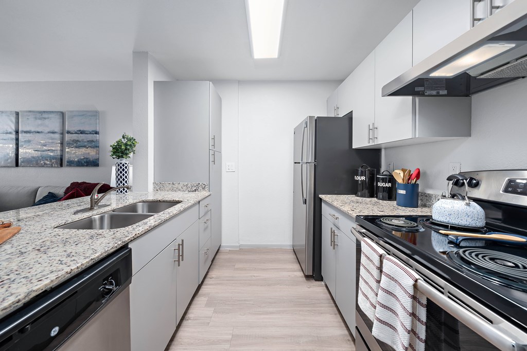 A modern kitchen with a black fridge and stove top oven.