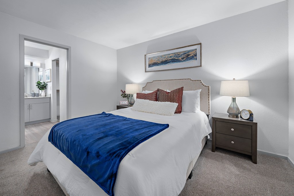 A bedroom with a large bed and a painting on the wall.