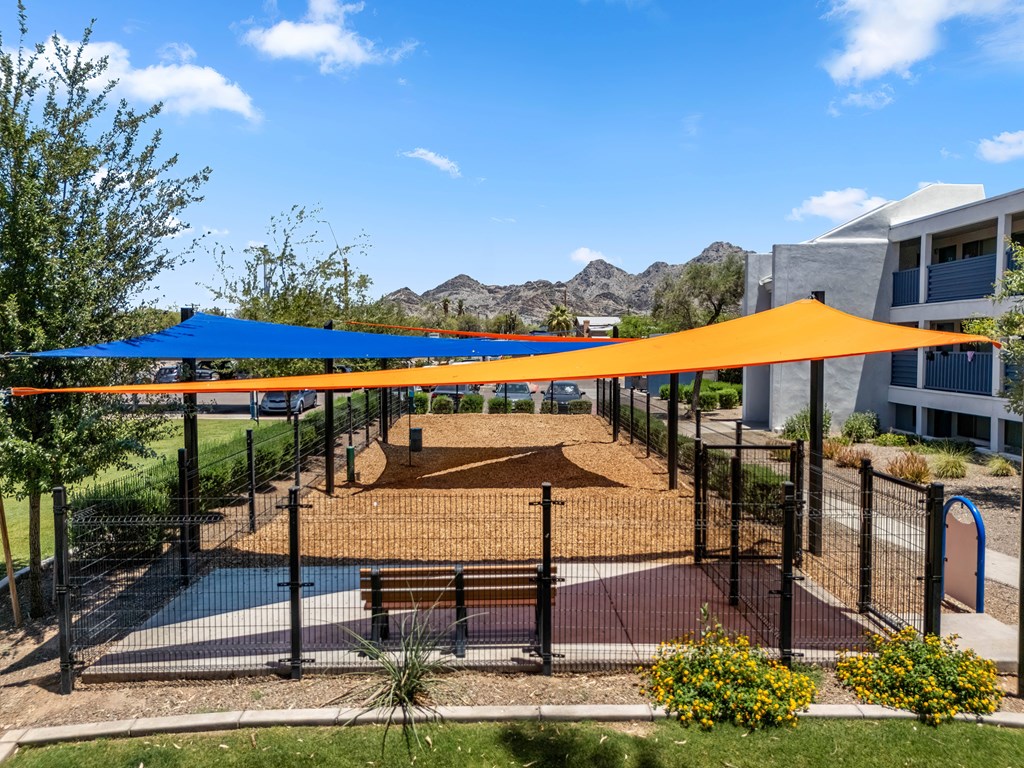 A playground with a blue and orange canopy.