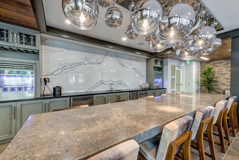 a kitchen with a long counter and chairs at a table