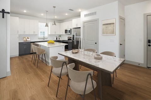 an open kitchen and dining area with a marble table and chairs