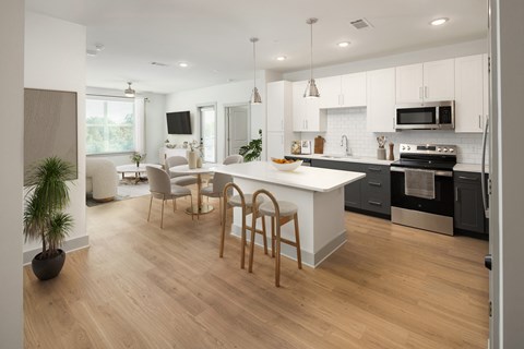 an open kitchen and dining area with a white island and black appliances