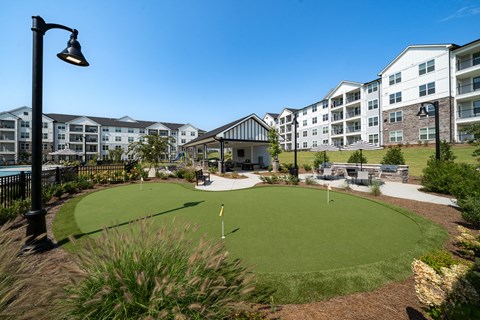 A golf green is in the middle of a courtyard surrounded by buildings.