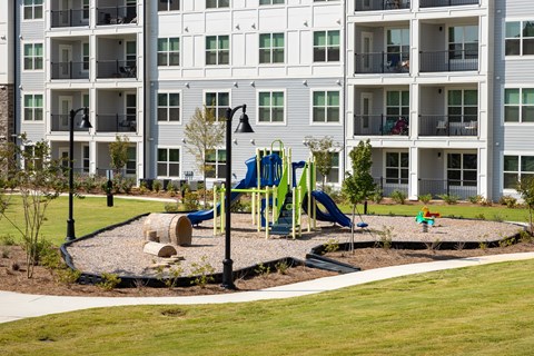 A playground with a slide and a green slide in front of a building.