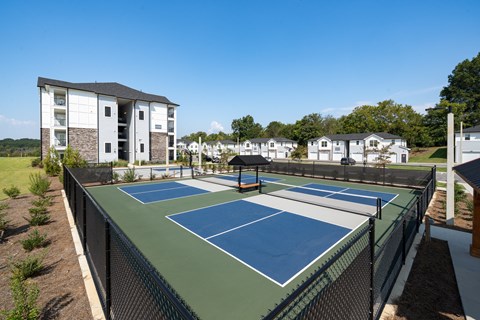 A tennis court is surrounded by a fence and apartment buildings.