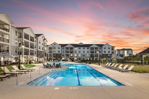 A swimming pool in front of apartment buildings at sunset.