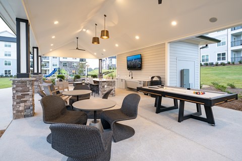 A patio with a table, chairs, and a television.