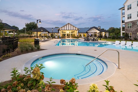 A large outdoor swimming pool surrounded by a black fence and a building in the background.