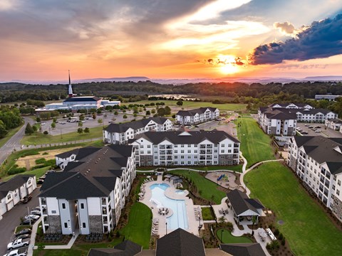 A sunset view of a resort with a pool and a church in the distance.