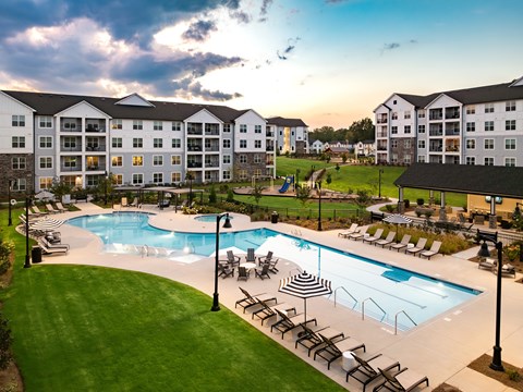 A large outdoor swimming pool surrounded by lounge chairs and umbrellas.