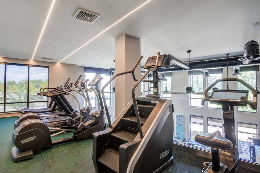 a gym with cardio equipment and a pool in the background