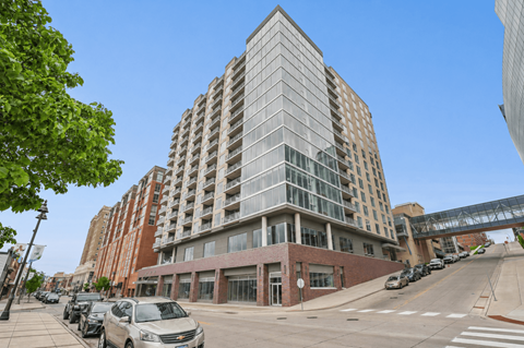 A tall building with a glass facade stands in the middle of a city street.