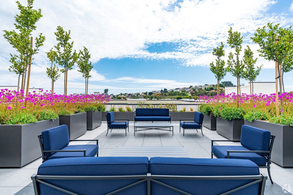a terrace with blue couches and chairs and flowers