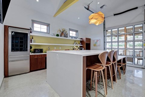 A kitchen with a white counter and wooden chairs.