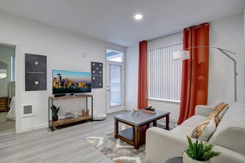 A living room with a grey couch, a coffee table, and a painting on the wall.